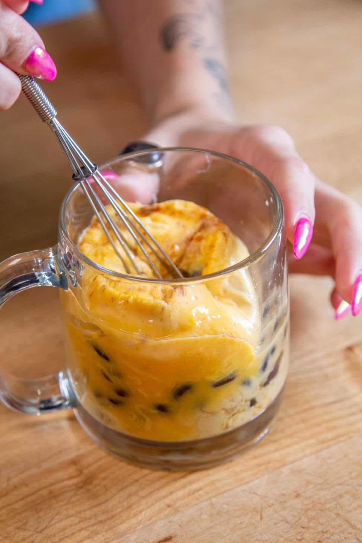 Whisk mixing eggs in clear mug