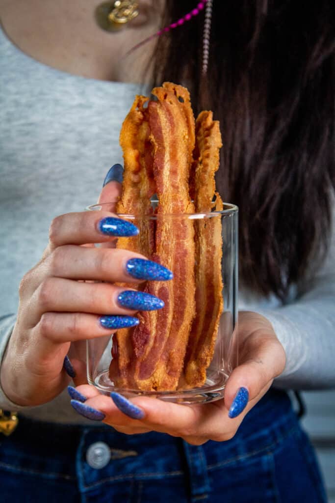 hands holding a cup of bacon