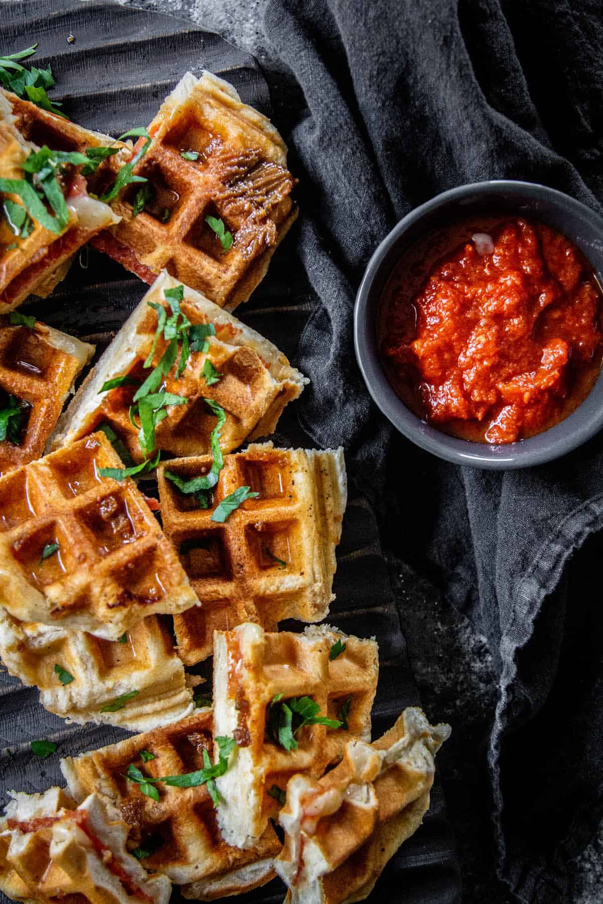 Platter full of waffle pizza slices next to a bowl of marinara sauce