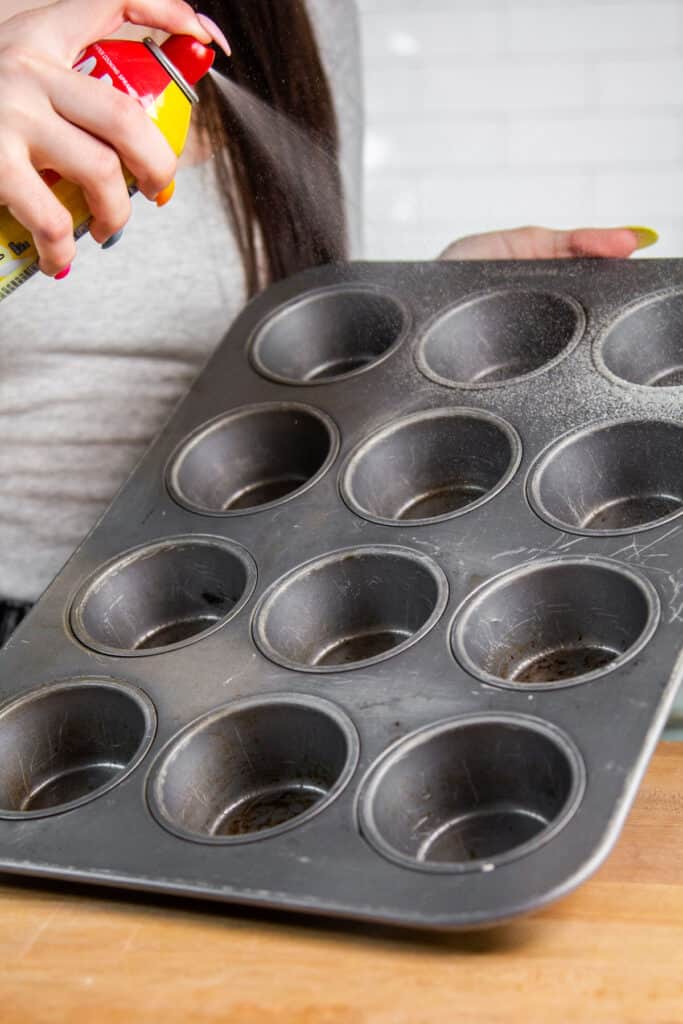 spraying muffin tin with spam