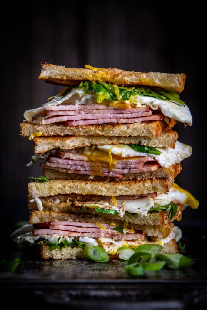4 fry egg sandwich halves stacked on a dark background