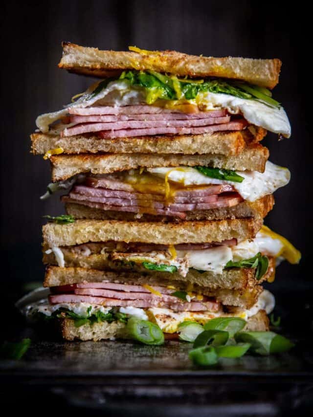 4 fry egg sandwich halves stacked on a dark background