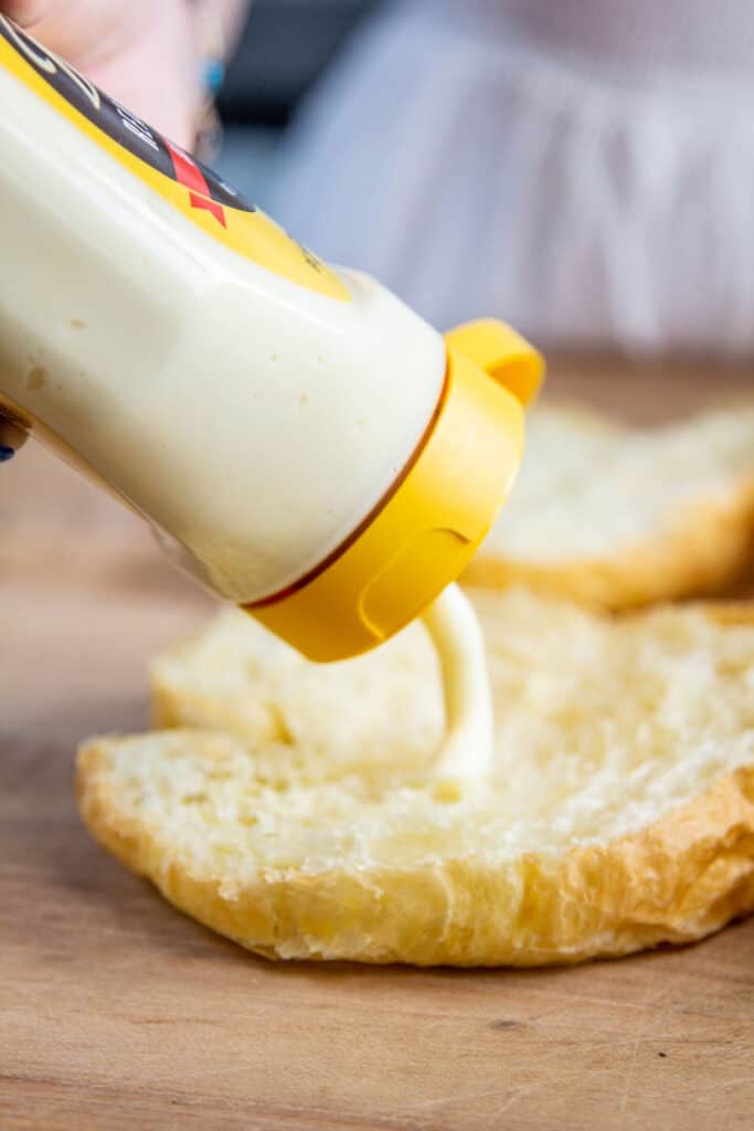 squeezing mayo onto croissant