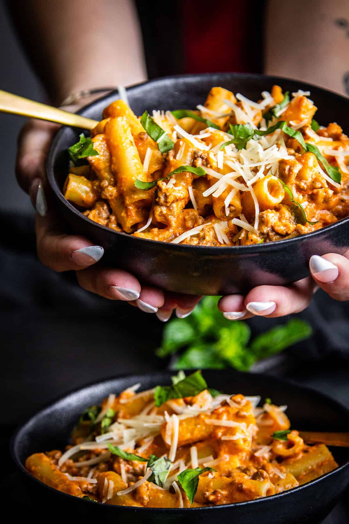 hands holding a bowl of pasta