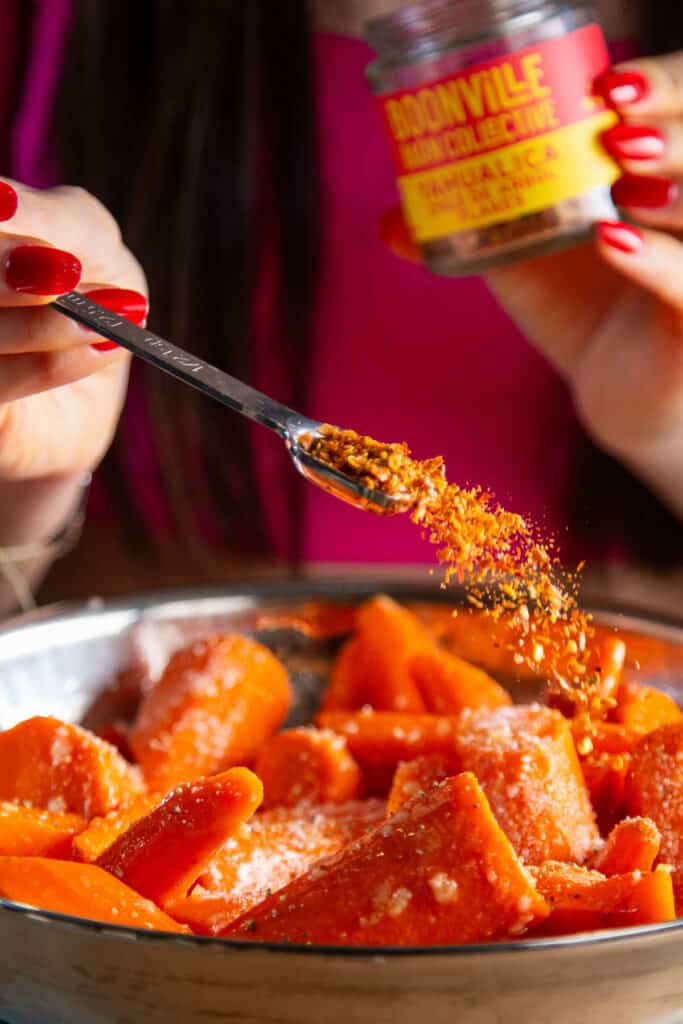 sprinkling red chili flakes on carrots